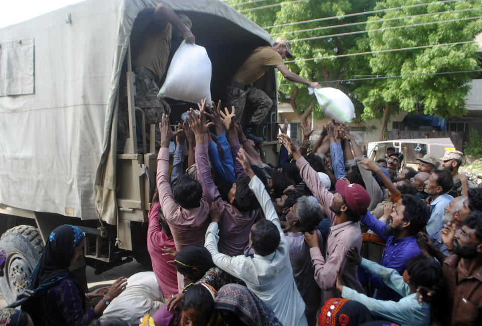 FILE - Army troops distribute food and other stuff to displaced people in a flood-hit area in in Hyderabad, Pakistan, Aug. 27, 2022. The flooding has all the hallmarks of a catastrophe juiced by climate change, but it is too early to formally assign blame to global warming, several scientists tell The Associated Press. (AP Photo/Pervez Masih, File)