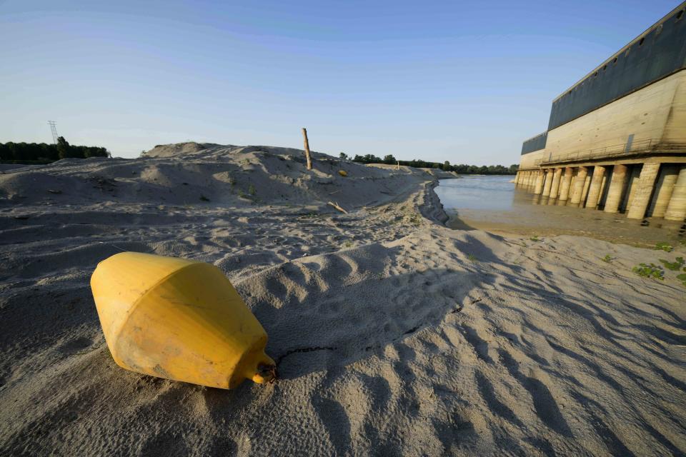 A buoy lies on the bed of the Po river in front of a dewatering pumps in Boretto, Italy, Wednesday, June 15, 2022. The drying up of the river is jeopardizing drinking water in Italy's densely populated and highly industrialized districts and threatening irrigation in the most intensively farmed part of the country. (AP Photo/Luca Bruno)