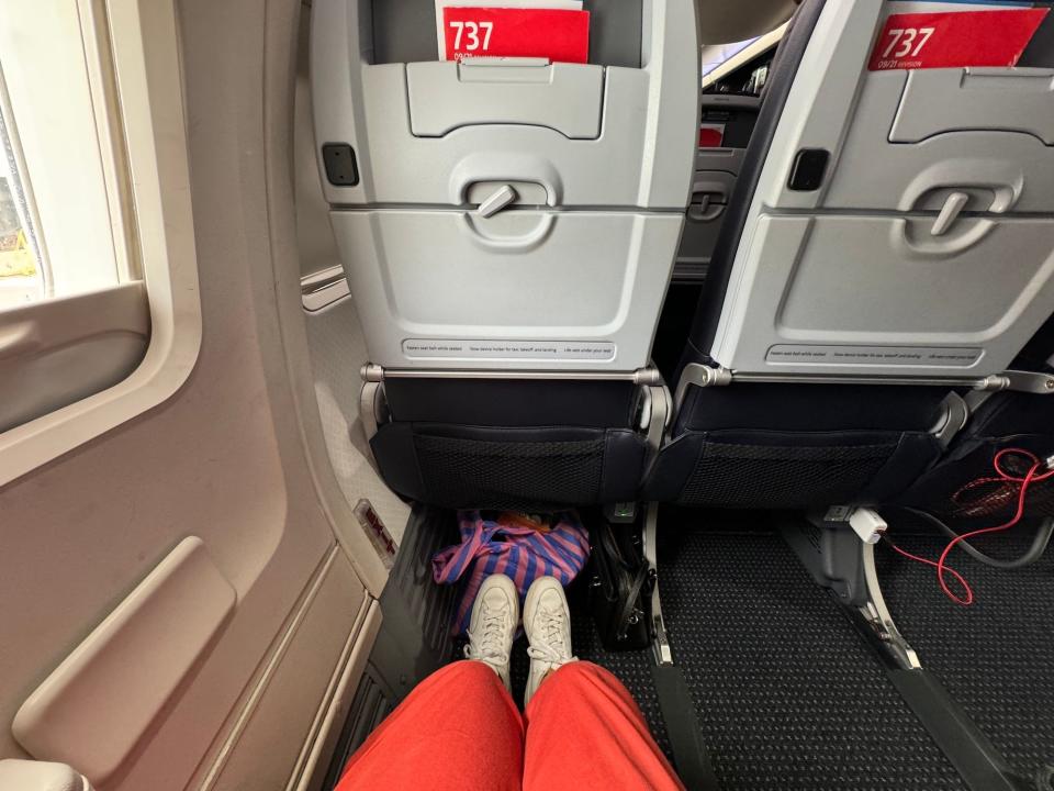 A view of a person's legs and sneakers showing the legroom in an exit-row seat in economy.