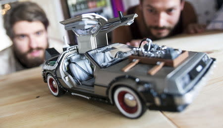 The director and actor at copy & waste Steffen Klewar (L) and actor Daniel Brunet pose behind a car model of a DeLorean DMC-12 at the concept store "Knick-Knack to the Future" in Berlin, Germany, September 1, 2015. REUTERS/Hannibal Hanschke