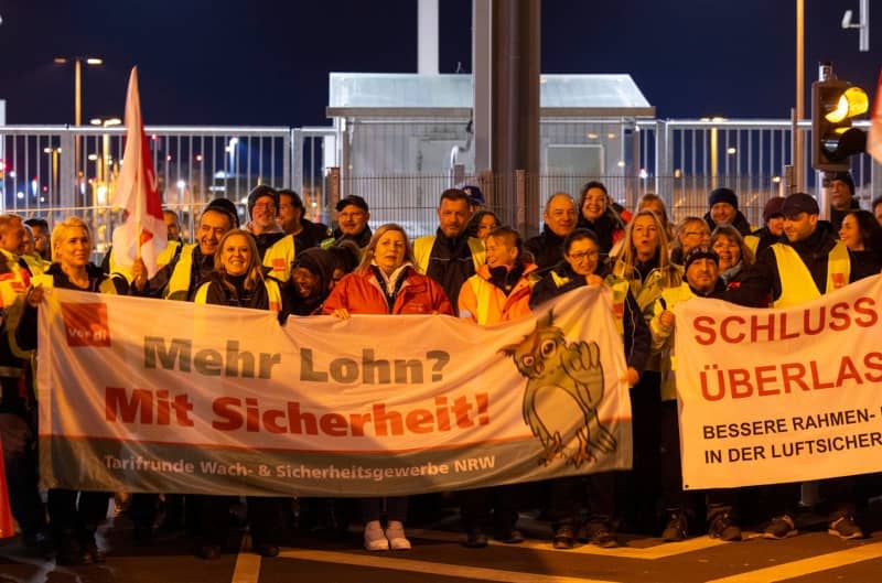 Striking airport security workers hold a banner reading "More pay? With security" at Cologne Bonn Airport, one of 11 major German airports that have started a one-day strike. Thomas Banneyer/dpa