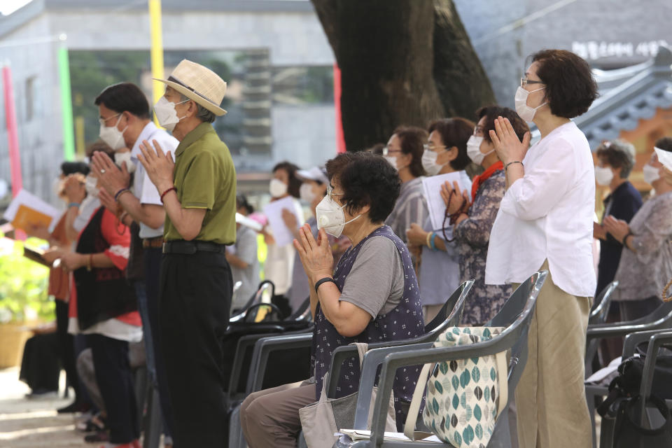 People wearing face masks to help protect against the spread of the coronavirus pray while maintaining social distancing during a service at the Chogyesa temple in Seoul, South Korea, Sunday, Aug. 23, 2020. (AP Photo/Ahn Young-joon)