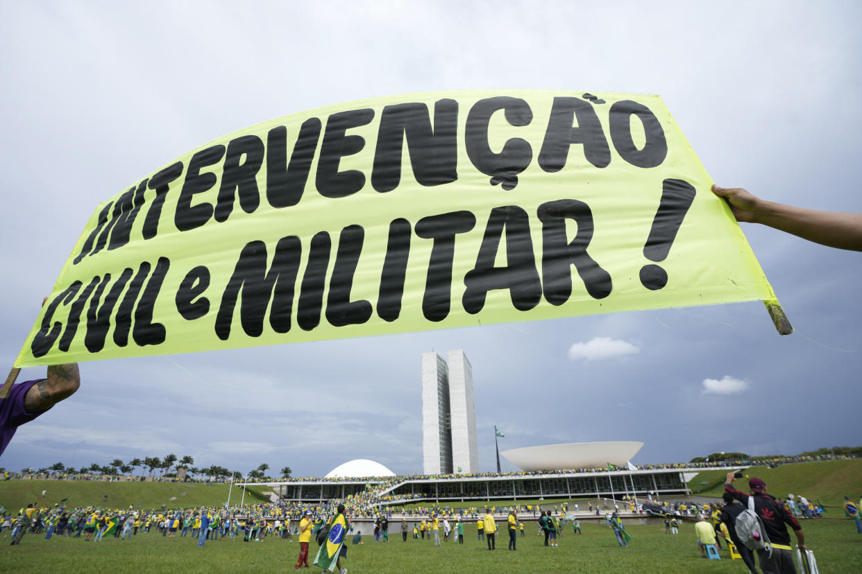 Protesters, supporters of Brazil's former President Jair Bolsonaro, hold a banner that reads in Portuguese "Civil and Military Intervention!" as others storm the the National Congress building in Brasilia, Brazil, Sunday, Jan. 8, 2023. (AP Photo/Eraldo Peres)