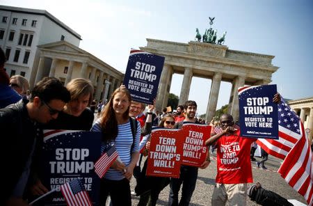 Campaigners pose with 'Stop Trump' signs in front of the Brandenburg Gate to urge Americans living abroad to register and vote in Berlin, Germany, September 23, 2016. REUTERS/Axel Schmidt