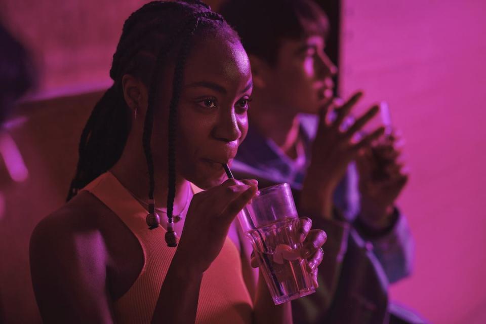 young woman drinking drink with male friend at illuminated bowling alley