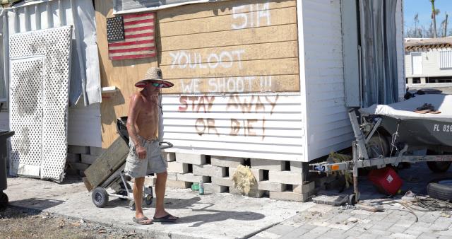 Curtis Eggleston, 59, carries some of his belongings out of his home damaged by Hurricane Ian on Pine Island, Fla., Monday.