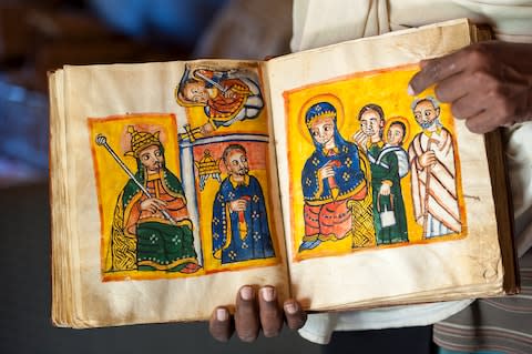 A priest shows an ancient book - Credit: GETTY