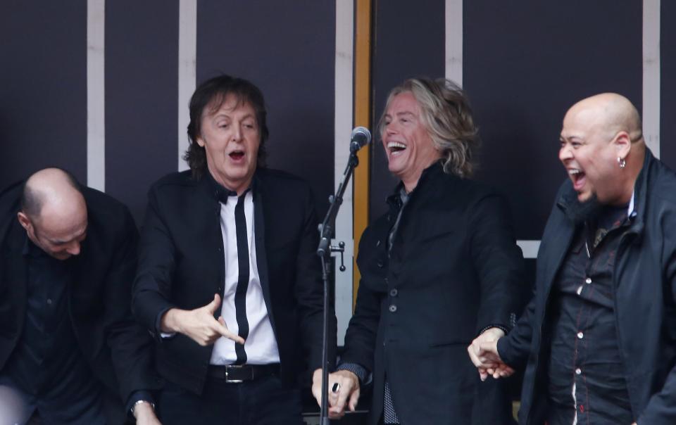 Paul McCartney gestures to audience as he leaves the stage with his band after playing surprise mini-concert in New York's Times Square