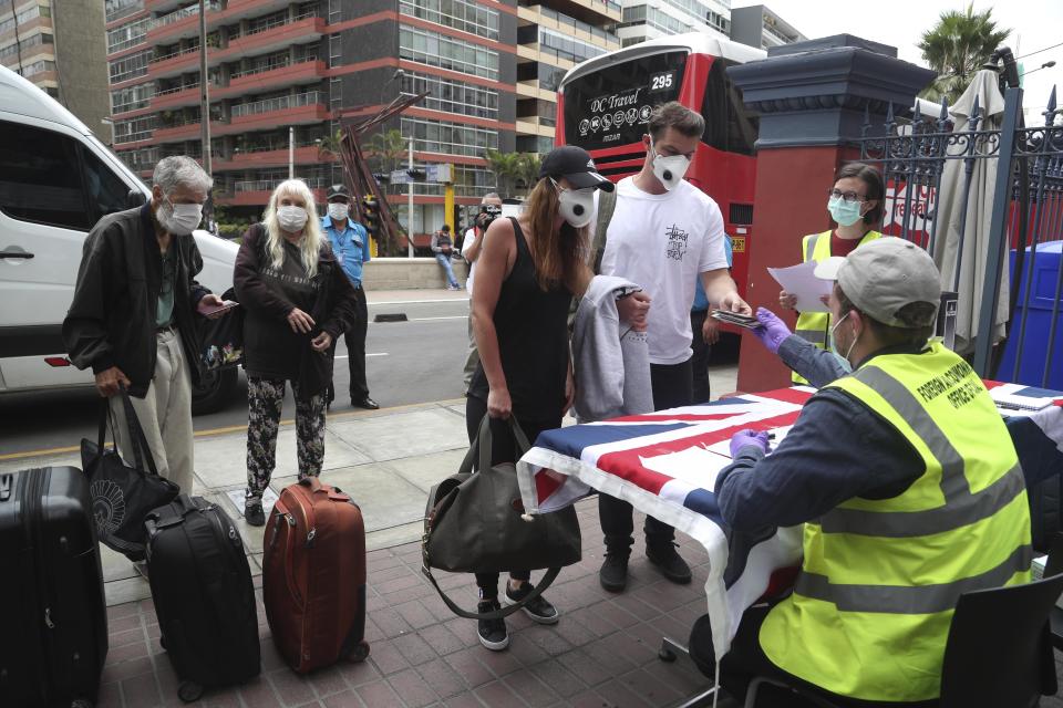 Ciudadanos británicos presentan sus documentos antes de tomar el autobús para ir al aeropuerto y tomar un avión rumbo a casa en Lima, Perú, el miércoles 25 de marzo de 2020. (AP Foto/Martin Mejia)