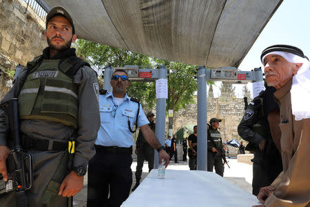 Israeli police officers stand guard next to newly installed metal detectors as a Palestinian man stands nearby at the entrance to the compound known to Muslims as Noble Sanctuary and to Jews as Temple Mount, in Jerusalem's Old City July 16, 2017. REUTERS/Ammar Awad