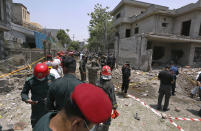 Police officers, investigators and rescue workers gather at the site of explosion, in Lahore, Pakistan, Wednesday, June 23, 2021. A powerful explosion ripped through a residential area in the eastern city of Lahore on Wednesday, killing some people and injuring some others, police and rescue officials said. (AP Photo/K.M. Chaudary)