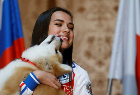 Russian figure skating gold medallist Alina Zagitova kisses an Akita Inu puppy presented to her in Moscow, Russia May 26, 2018. REUTERS/Maxim Shemetov