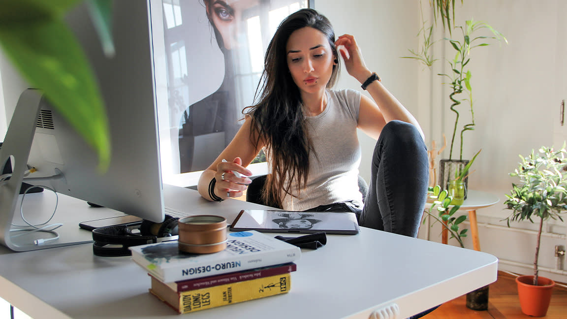  Artist in residence, a woman sits at an art desk with a cat. 