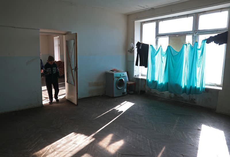 Refugees from Nagorno-Karabakh region walk through the disused library where they temporarily live in Masis