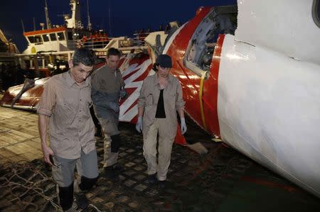 Investigators walk near a section of the tail of AirAsia QZ8501 passenger plane in Kumai Port, near Pangkalan Bun, central Kalimantan January 11, 2015. REUTERS/Darren Whiteside