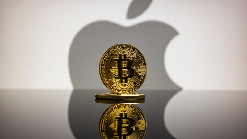 Physical cryptocurrency coins of Bitcoin (BTC) in front of the logo of Apple