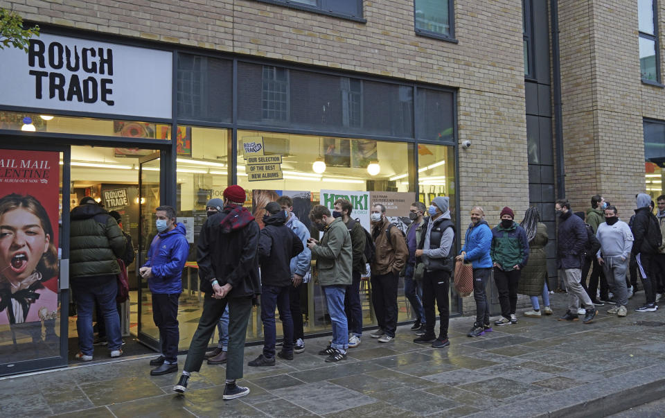 People queue outside Rough Trade in Bristol, England Saturday Dec. 11, 2021 where a T-shirt designed by street artist Banksy is being sold to support four people facing trial accused of criminal damage in relation to the toppling of a statue of slave trader Edward Colston. The anonymous artist posted on Instagram pictures of limited edition grey souvenir T-shirts which will go on sale on Saturday in Bristol. The shirts have a picture of Colston's empty plinth with a rope hanging off, with debris and a discarded sign nearby. (Jacob King/PA via AP)