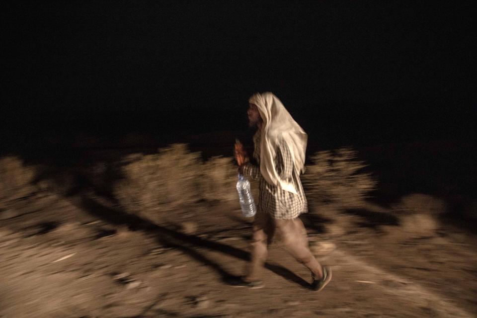 In this July 12, 2019 photo, 35-year-old Mohammed Eissa walks along a highway, around 50 kilometers (31 miles) from Djibouti. Eissa picked up rides from his home to the border with Djibouti, then walked. His second day there, he was robbed at knifepoint by several men who took his money. The next day, he walked six hours in the wrong direction, back toward Ethiopia, before he found the right path again. (AP Photo/Nariman El-Mofty)