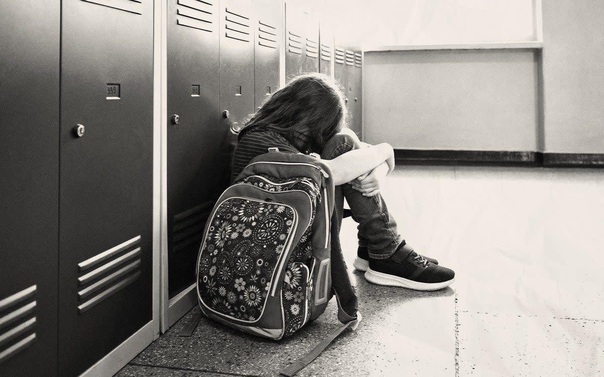 distressed girl sat on floor by school lockers