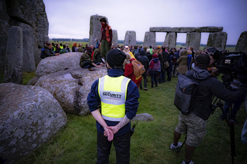 Security keep watch as people stand inside the stone circle during Summer Solstice at Stonehenge, where some people jumped over the fence to enter the stone-circle to watch the sun rise at dawn of the longest day of the year in the UK, in Amesbury, England, Monday June 21, 2021. The prehistoric monument of ancient stones have been officially closed for the celebrations due to the coronavirus lockdown, but groups of people ignored the lockdown to mark the Solstice, watched by low key security. (Ben Birchall/PA via AP)