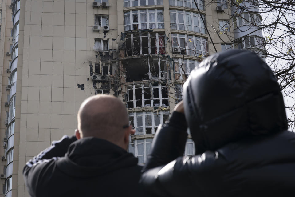 People watch an apartment building damaged by a drone that was shot down, during a Russian overnight strike, amid Russia's attack, in Kyiv, Ukraine, Monday, May 8, 2023. (AP Photo/Andrew Kravchenko)