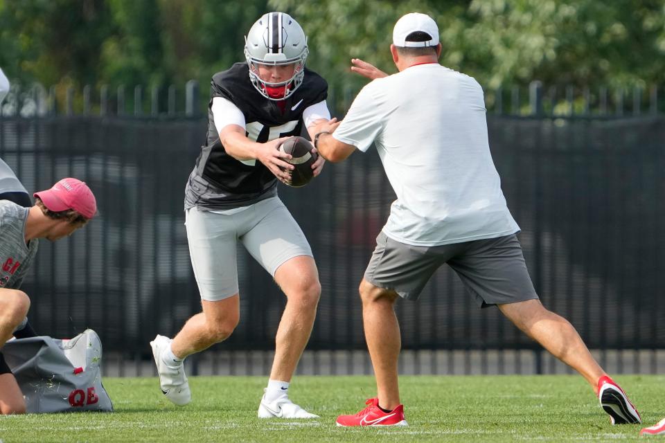 Aug 4, 2022; Columbus, OH, USA;  Ohio State Buckeyes quarterback Devin Brown (15) takes a snap in front of head coach Ryan Day during the first fall football practice at the Woody Hayes Athletic Center. Mandatory Credit: Adam Cairns-The Columbus Dispatch