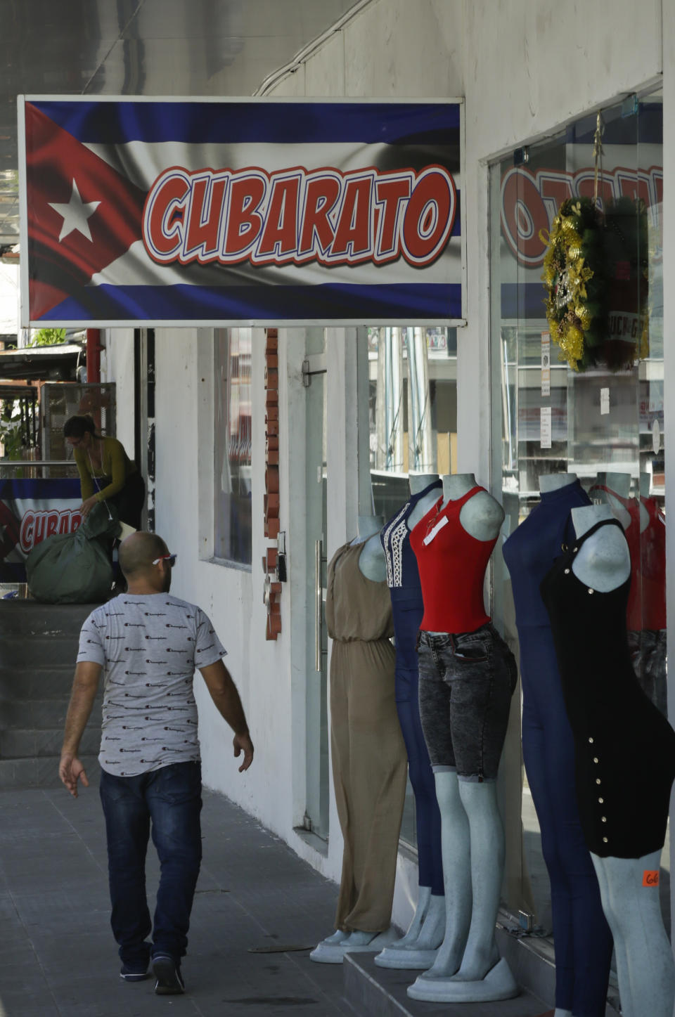 A sign in Spanish that makes a play on words by combining the words "Cuban" and "Cheap" hangs outside a duty free shop in the Colon Free Trade Zone in Colon City, Panama, Friday, Dec. 7, 2018. The Colon Free Trade Zone has a “Little Havana” where Cubans spent $308 million in 2017, and are on track in spend perhaps 8 percent more in 2018, said Luis Carlos Saenz, the zone’s general assistant manager. (AP Photo/Arnulfo Franco)