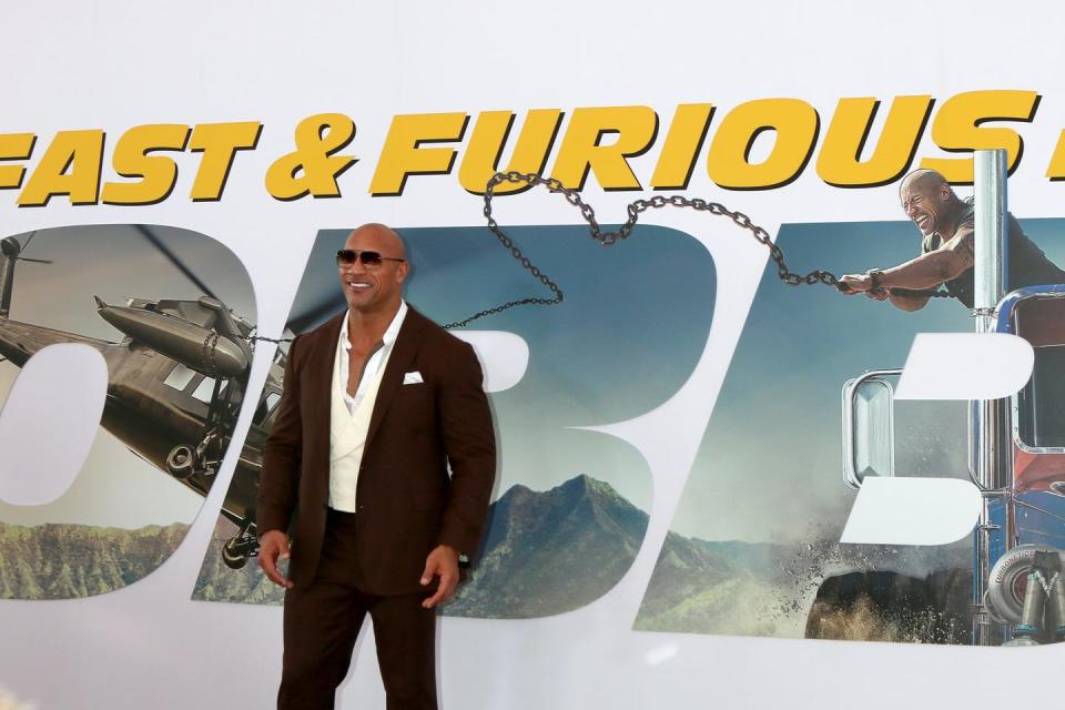 Dwayne Johson standing inn front of a promotional poster for Fast & Furious