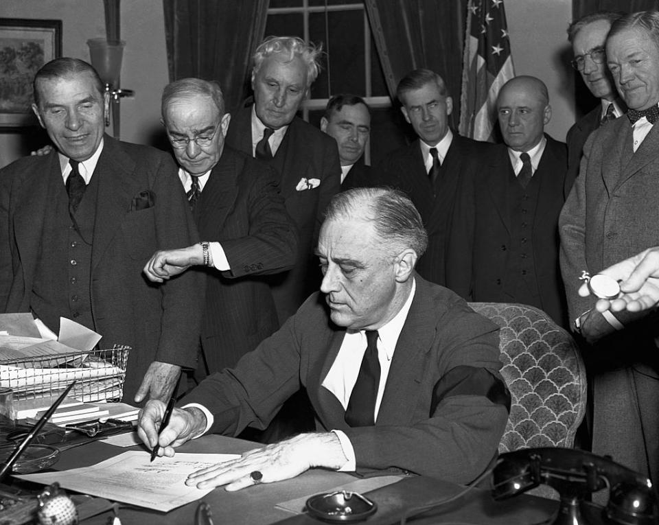 Cabinet members watch with mixed emotions as President Franklin D. Roosevelt, wearing a black armband, signs the United States' declaration of war against Japan at 4:10 p.m. Washington time on Dec. 8, 1941.<span class="copyright">Bettmann</span>