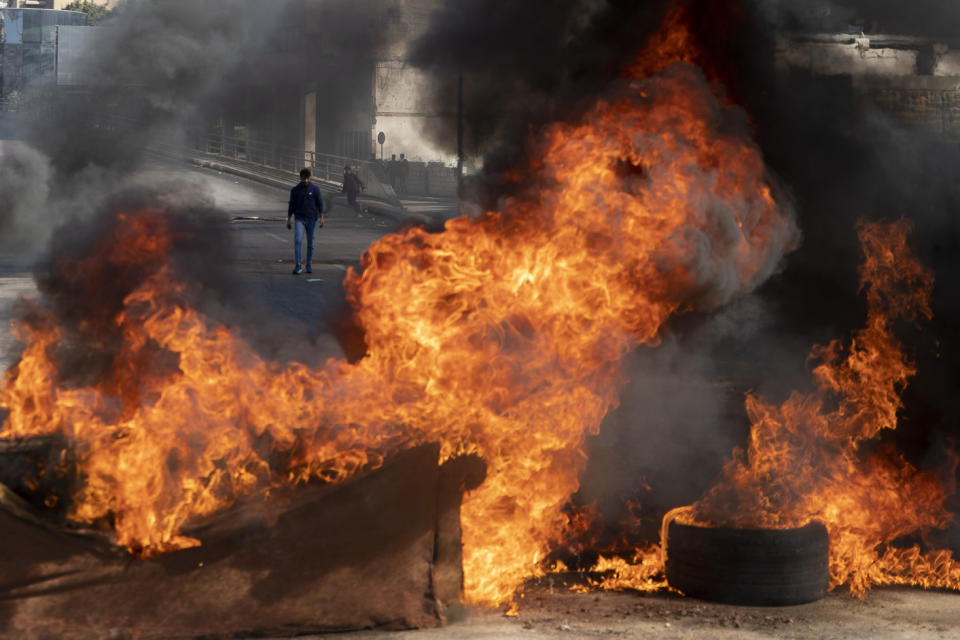 Protesters burn tires to close a main road, after the Lebanese pound hit a record low against the dollar on the black market, in Beirut, Lebanon, Saturday, March 6, 2021. (AP Photo/Hassan Ammar)