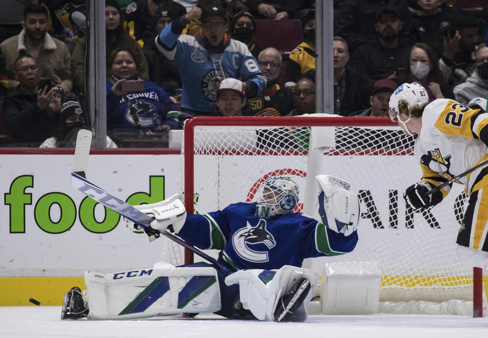 Vancouver Canucks goalie Thatcher Demko makes a save as Pittsburgh Penguins' Brock McGinn watches during the second period of an NHL hockey game Saturday, Dec. 4, 2021, in Vancouver, British Columbia. (Darryl Dyck/The Canadian Press via AP)