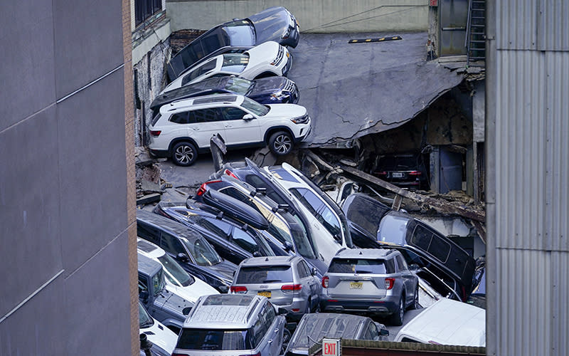 Cars are seen piled on top of each other at the scene of a partial collapse of a parking garage