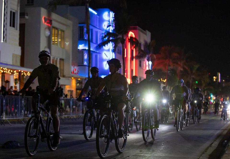 Police officers ride bikes down Ocean Drive before the start of a midnight curfew during spring break on Friday, March 15, 2024, in Miami Beach.