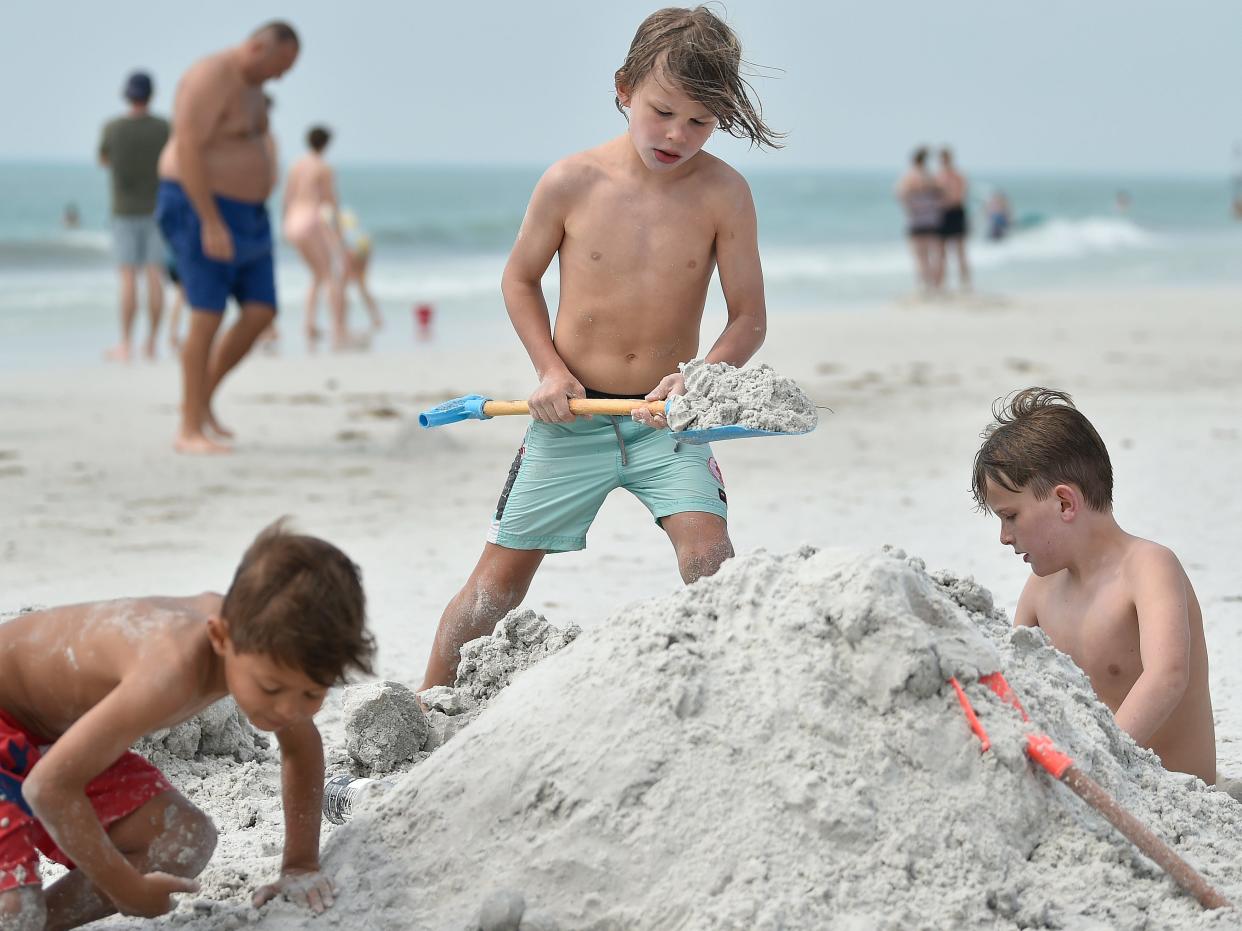 Three young friends  build a sandcastle on Siesta Beach in March, when thousands of people flocked to Siesta for spring break.