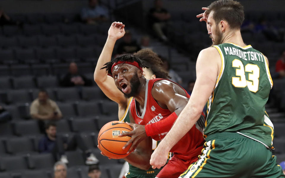 New Mexico forward Morris Udeze (24) drives past San Francisco center Volodymyr Markovetskyy (33) during the first half of an NCAA college basketball game Monday, Dec. 12, 2022, in Las Vegas. (AP Photo/Steve Marcus)