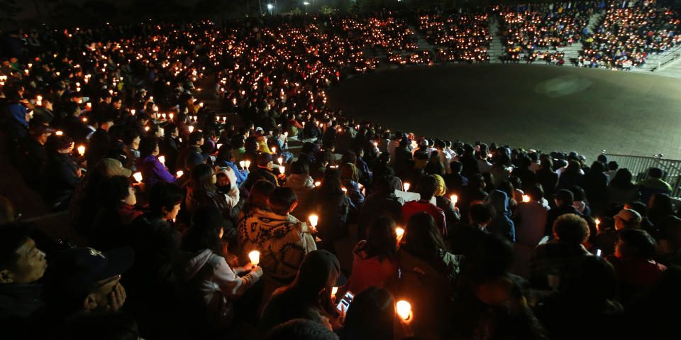 Danwon high school students and citizens hold candles as they pray for the safe return of passengers of the sunken Sewol ferry in Ansan, South Korea, Sunday, April 20, 2014. Divers recovered more bodies from inside the ferry that sank off South Korea, pushing the confirmed death toll to over three dozen. The discovery came after rescuers finally gained access to the inside of the ship following three days of failure and frustration caused by strong currents and bad visibility due to inclement weather. (AP Photo/Yonhap) Korea Out