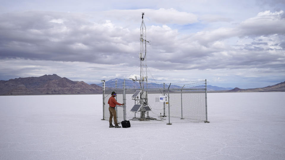 A state geologist collects data from a weather station in the Bonneville Salt Flats on Tuesday, Sept. 13, 2022, near Wendover, Utah. The state is funding a study to determine if flooding the landscape with salty water helps maintain the size of the flats and combats the effects of climate change, mining and racecar driving. (AP Photo/Rick Bowmer)