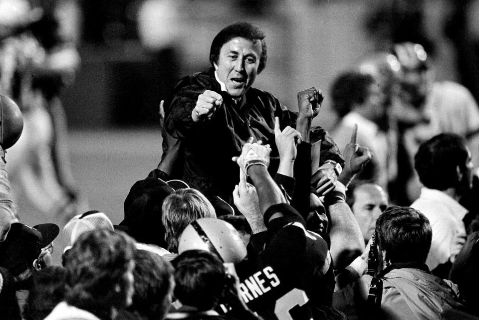 FILE - In this Jan. 23, 1984, file photo, coach Tom Flores gestures to members of the Los Angeles Raiders as they carry him off the field after their 38-9 victory over the Washington Redskins in Super Bowl XVIII in Tampa, Fla. Flores has been selected as the Coach Finalist for the Pro Football Hall of Fame’s Class of 2021. (AP Photo/File)
