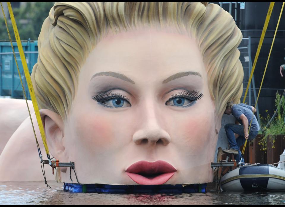 A man adjusts a sculpture "Giant Mermaid" on the Alster lake in the northern German city of Hamburg on August 1, 2011. The sculpture is created by art and advertising agency headed by Oliver Voss. 