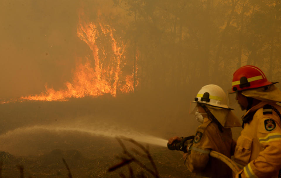 Firefighters work to contain a bushfire along Old Bar road in Old Bar, NSW.