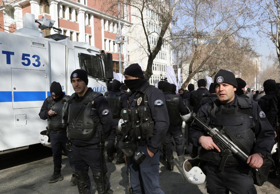 Riot police stand at the entrance to the Justice Ministry as members of Turkey's main opposition Republican People's Party, CHP, walk to the ministry building in Ankara, Turkey, Thursday, Feb. 6, 2014, demanding that the ministry sends to Parliament a summary of proceedings into four cabinet ministers who were dismissed after being implicated in a corruption and bribery scandal in December. The opposition parties accuse Prime Minister Recep Tayyip Erdogan's government of trying to cover up the scandal. (AP Photo/Burhan Ozbilici)