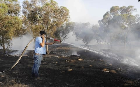 A firefighter extinguishes a fire in a forest field near the Kibbutz of Kissufim - Credit: MENAHEM KAHANA/AFP/Getty Images