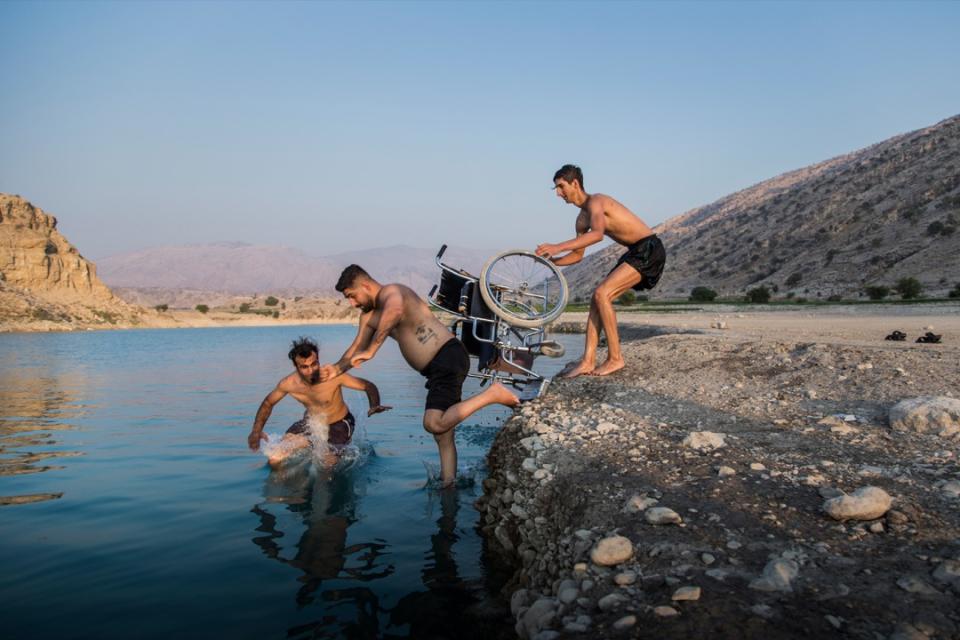 2020年9月9日，伊朗市鎮 Gachsaran，Saeed（中）的兄弟把他從輪椅中推到水塘裏，讓他能一嘗跳水的感覺。