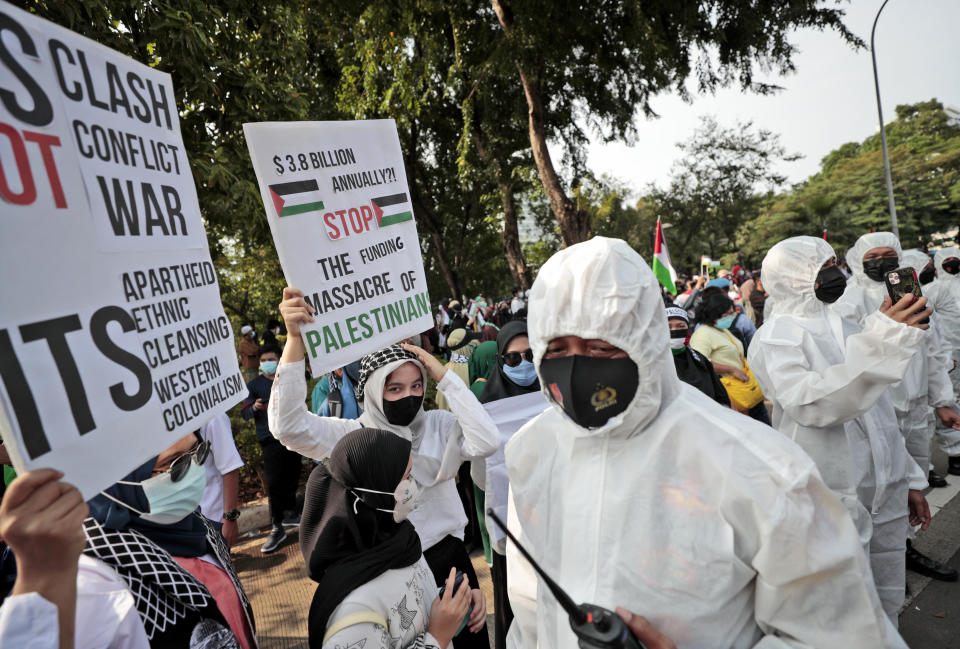 Police officers in protective suits call on protesters to maintain physical distancing to help curb the spread of coronavirus during an anti-Israel rally outside the U.S. Embassy in Jakarta, Indonesia, Tuesday, May 18, 2021. Pro-Palestinian protesters marched to the heavily guarded embassy on Tuesday to demand an end to Israeli airstrikes in the Gaza Strip. (AP Photo/Dita Alangkara)