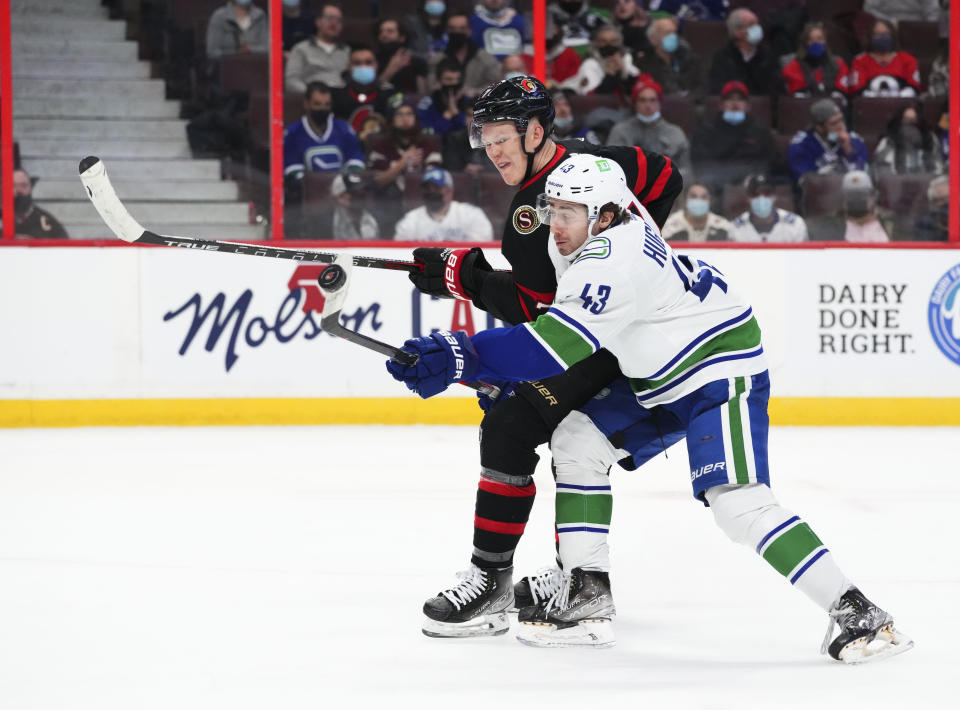 Ottawa Senators left wing Brady Tkachuk (7) battles for the puck with Vancouver Canucks defenseman Quinn Hughes (43) during the second period of an NHL hockey game, Wednesday, Dec.1, 2021 in Ottawa, Ontario. (Sean Kilpatrick/The Canadian Press via AP)