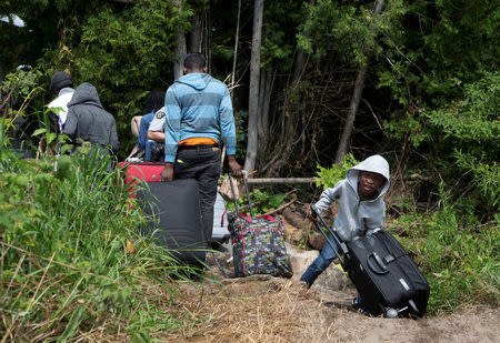 A family claiming to be from Haiti drag their luggage over the US-Canada border into Canada from Champlain, New York, U.S. August 3, 2017. REUTERS/Christinne Muschi