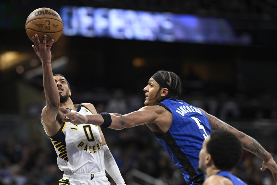 Indiana Pacers guard Tyrese Haliburton (0) is fouled by Orlando Magic forward Paolo Banchero (5) while going up to shoot during the second half of an NBA basketball game, Sunday, March 10, 2024, in Orlando, Fla. (AP Photo/Phelan M. Ebenhack)