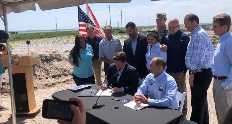 Surrounded by the state's top environment officials, Florida Gov. Ron DeSantis signs an agreement with the U.S. Army Corps of Engineers on Thursday, April 22, 2021. The agreement allows the federal agency to begin construction on the Everglades Agricultural Area Reservoir.