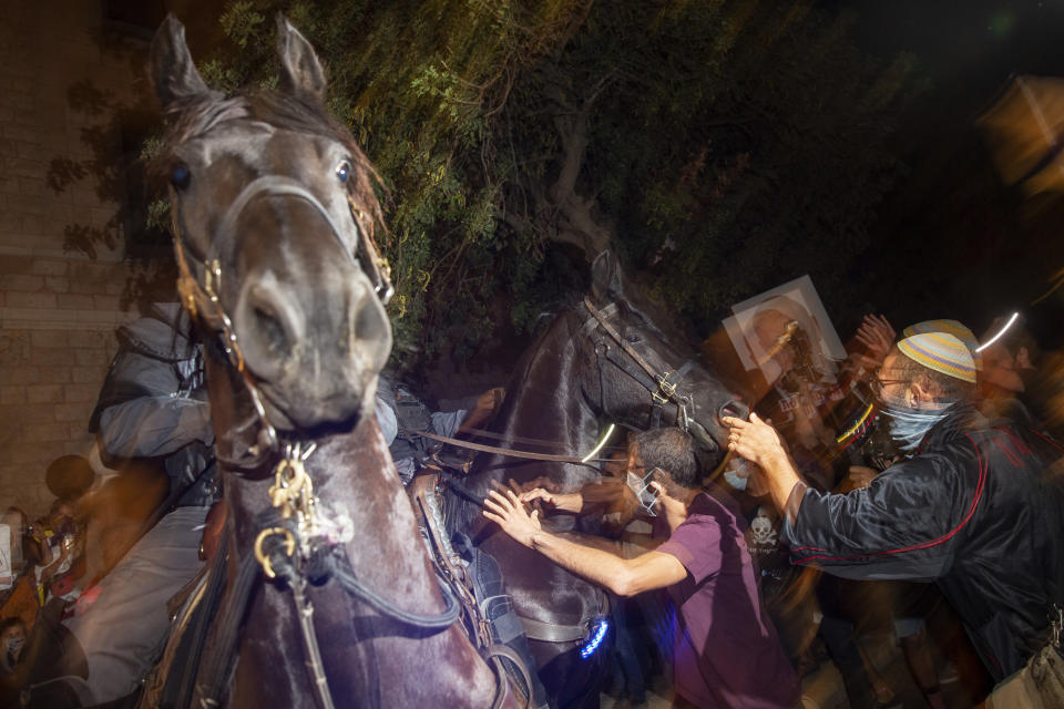 Israeli mounted police officers clash with demonstrators during a protest against Israel's Prime Minister Benjamin Netanyahu outside his residence in Jerusalem, Sunday, July 26, 2020. Protesters demanded that the embattled Israeli leader resign as he faces a trial on corruption charges and grapples with a deepening coronavirus crisis. (AP Photo/Ariel Schalit)