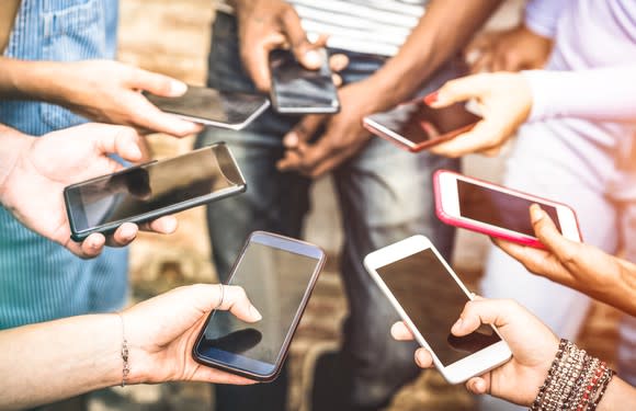 A group of friends using their smartphones in a circle.